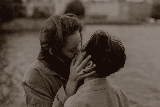 Couple kissing outside while the wind blows through their hair