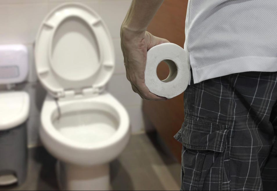 Person holding toilet paper roll near a toilet with the lid up in a bathroom