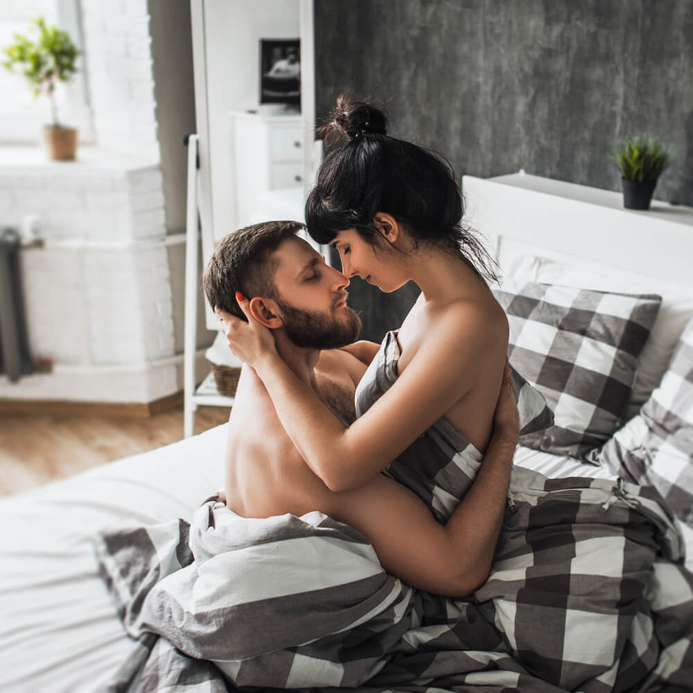 Hombre y mujer sentados en la cama abrazados