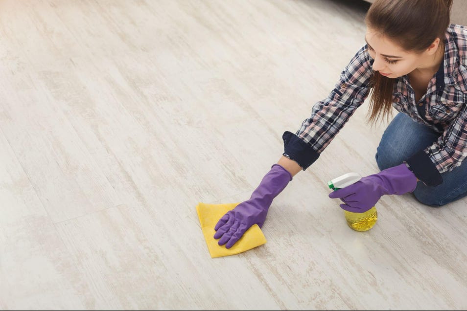 a person wearing gloves cleaning the vinyl floor using microfiber cloth