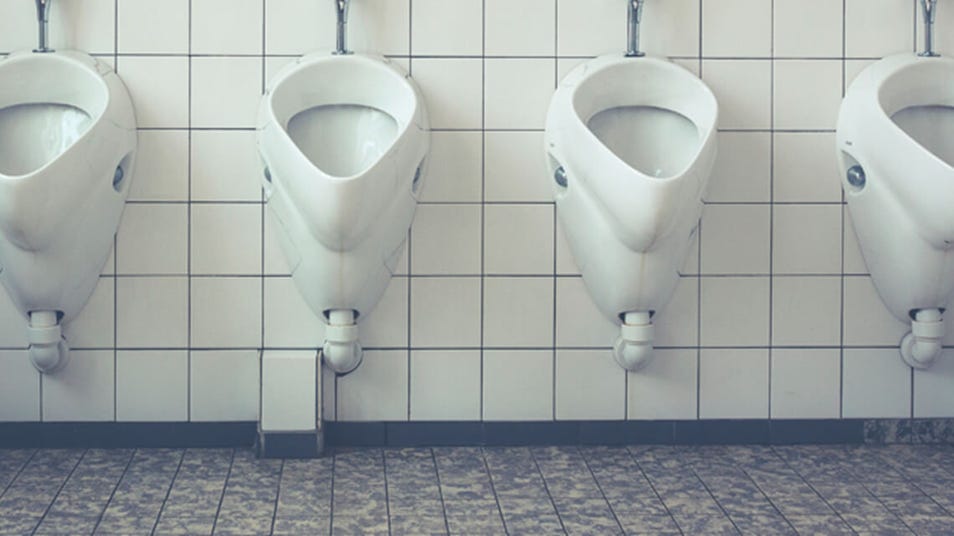 Three white urinals on a tiled wall in a restroom.