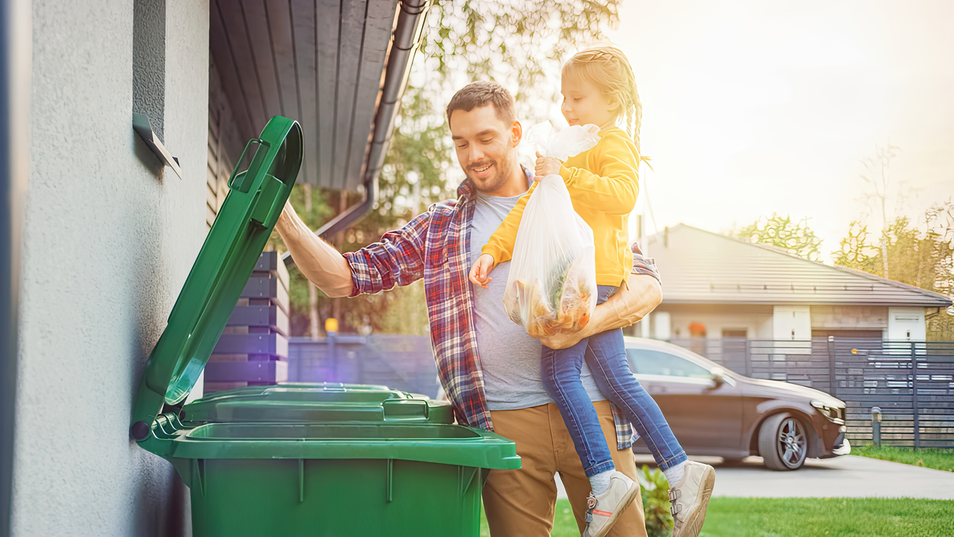 Father holding daughter while throwing away trash