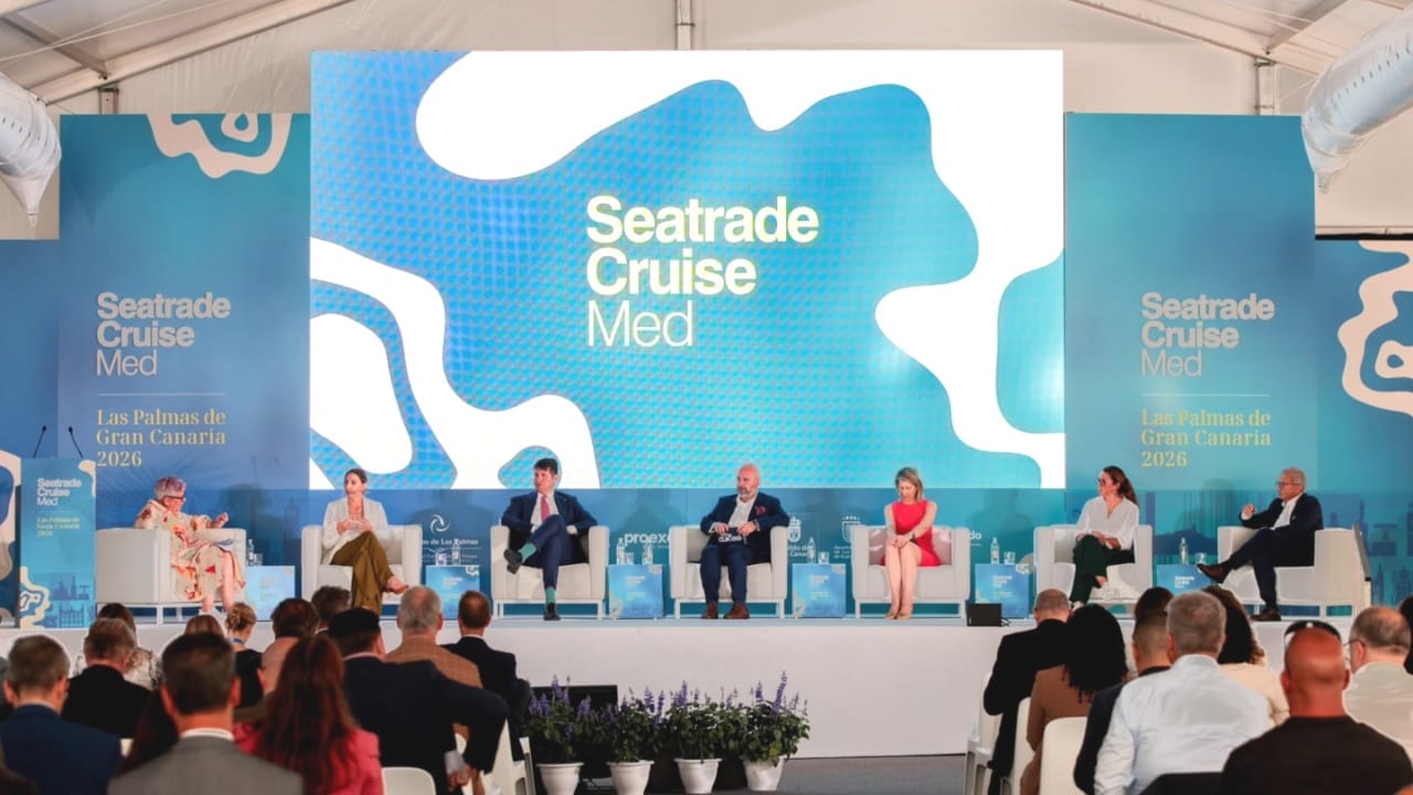 three women and four men sat on chairs on a stage for a panel discussion