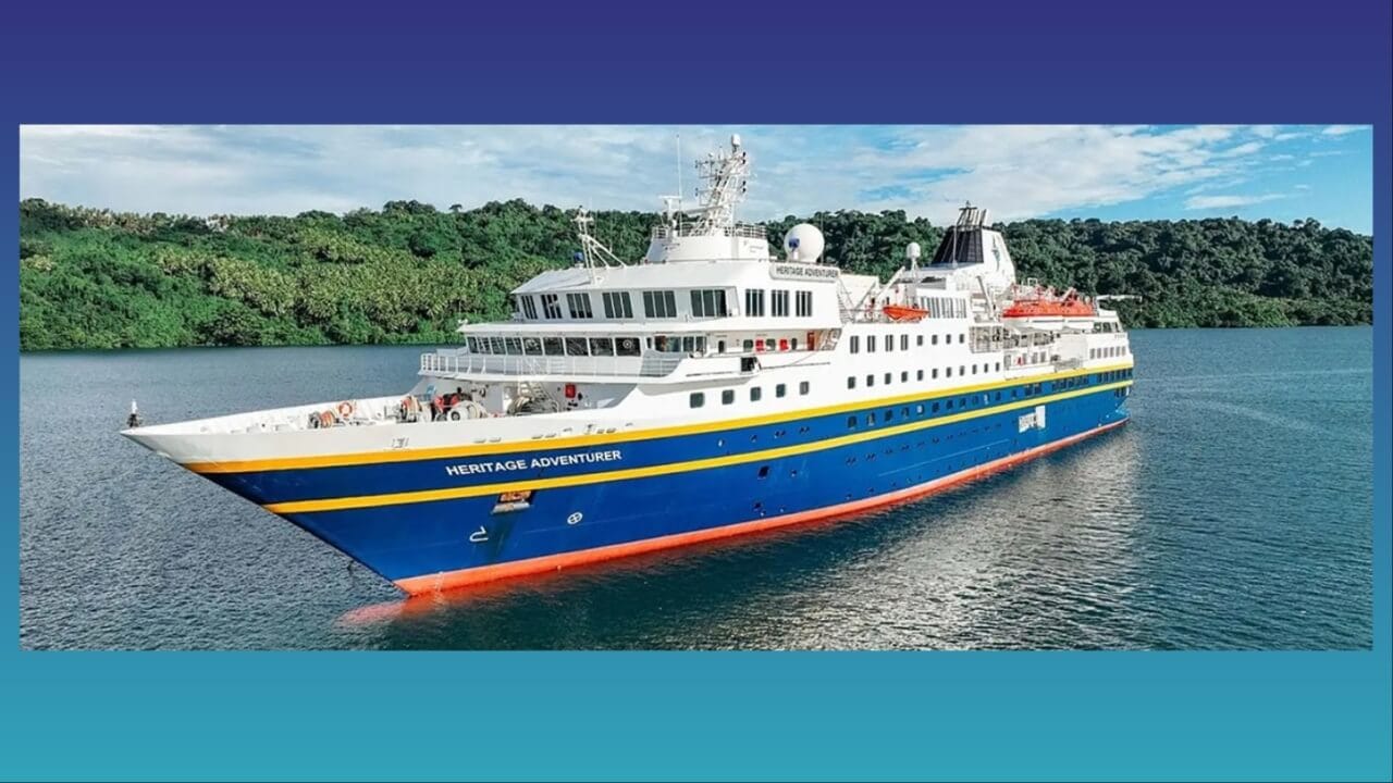 expedition cruise shp with blue hull and white superstructure near tree-lined shore