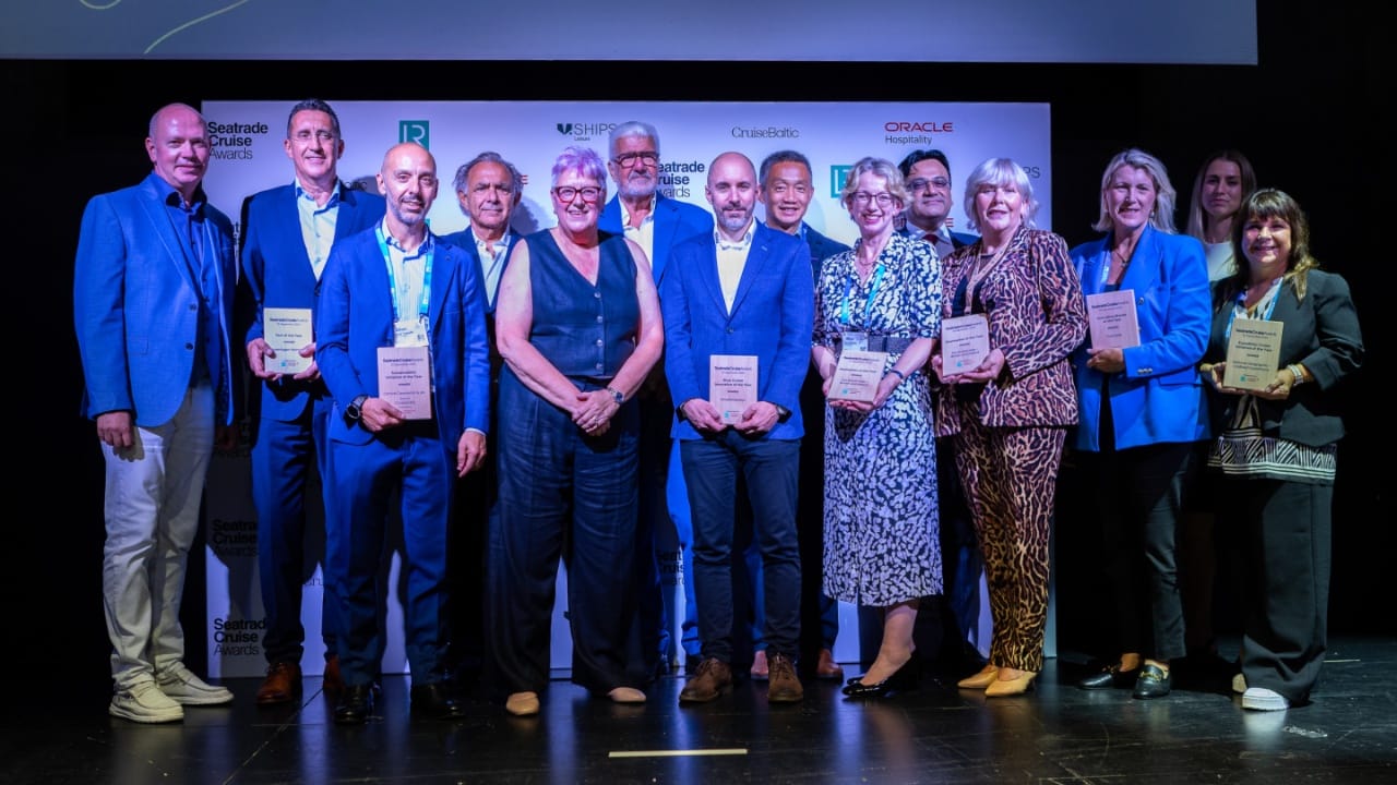 Un grupo de personas en un escenario, sonriendo, vistiendo atuendo formal
