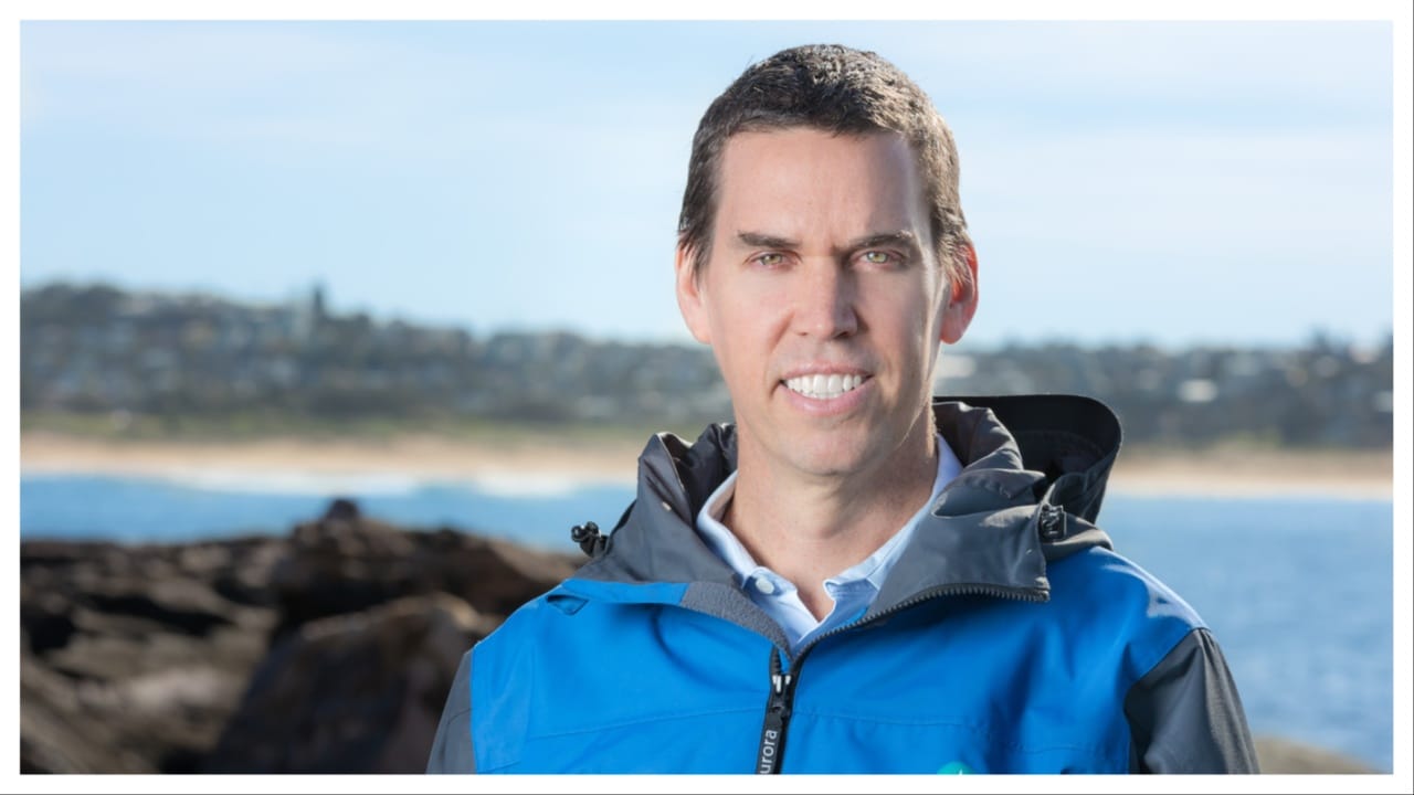smiling man with short brown hair in a blue anorak