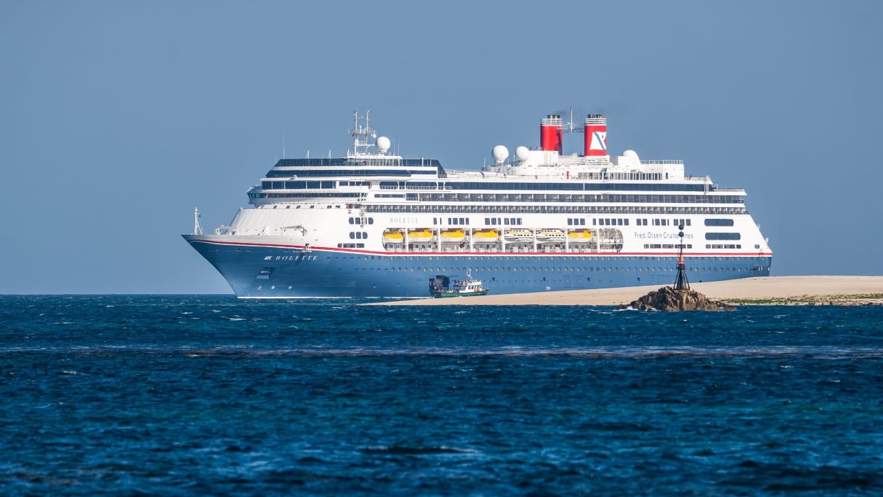 A white and blue cruise ship sailing on deep blue water