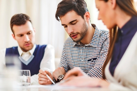 Three office workers sat reviewing documents