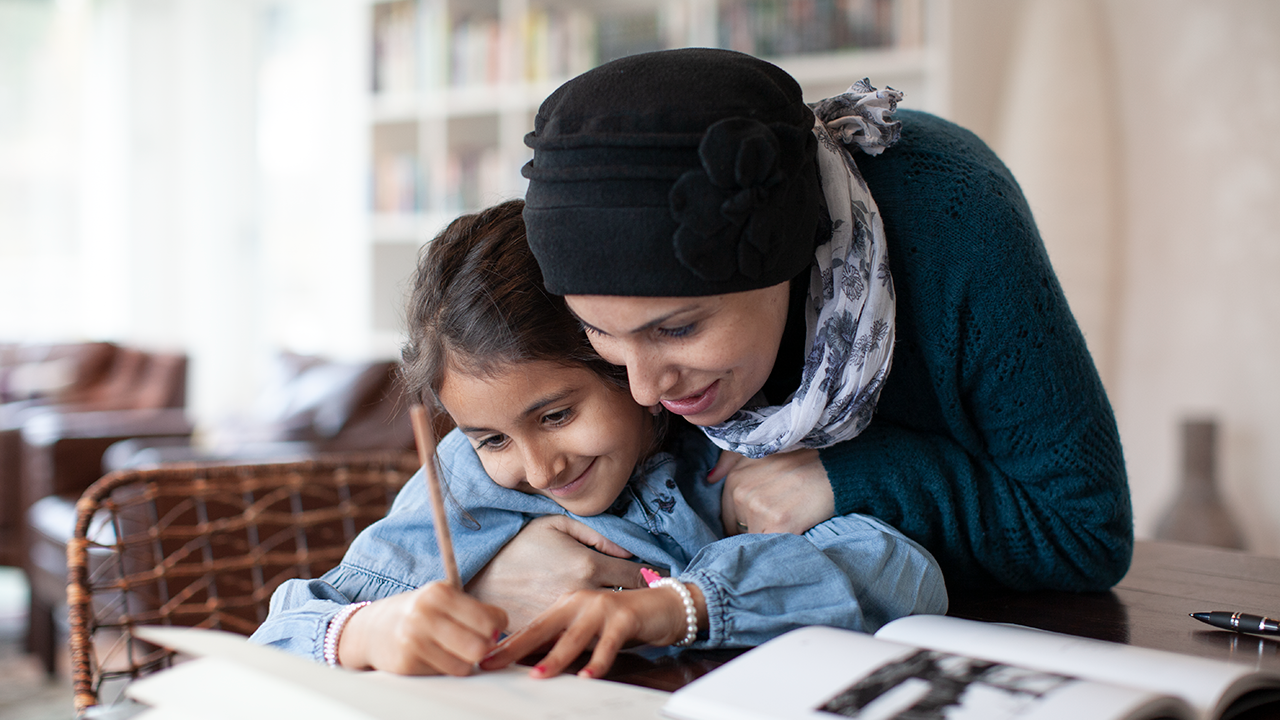 mother embracing daughter studying at home