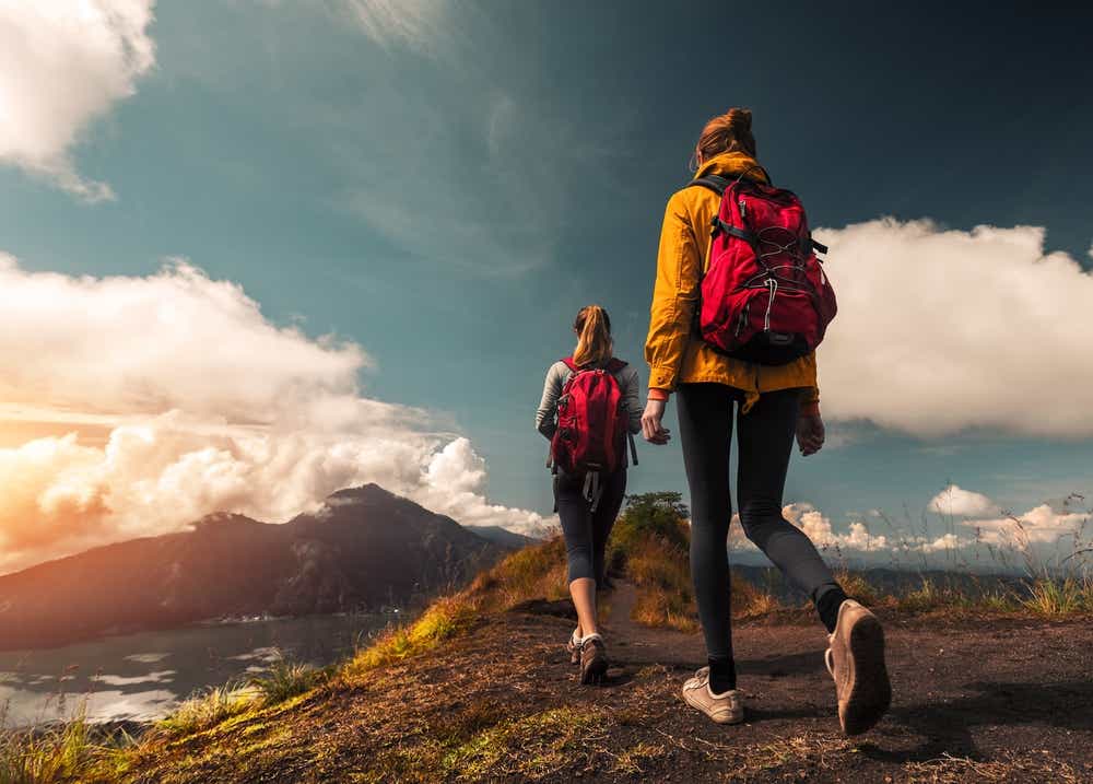 Two women are hiking towards a mountain. 