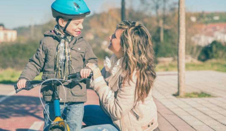 Pojke med cykel pratar med sin mamma