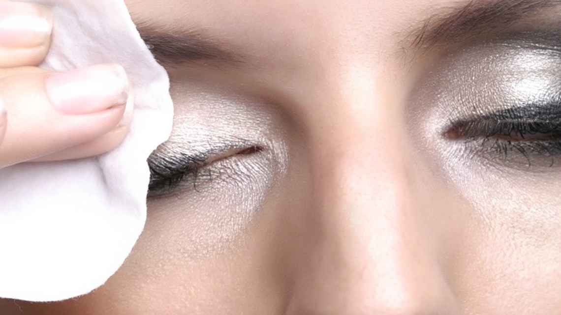 a woman wiping her eye lids with a wipe