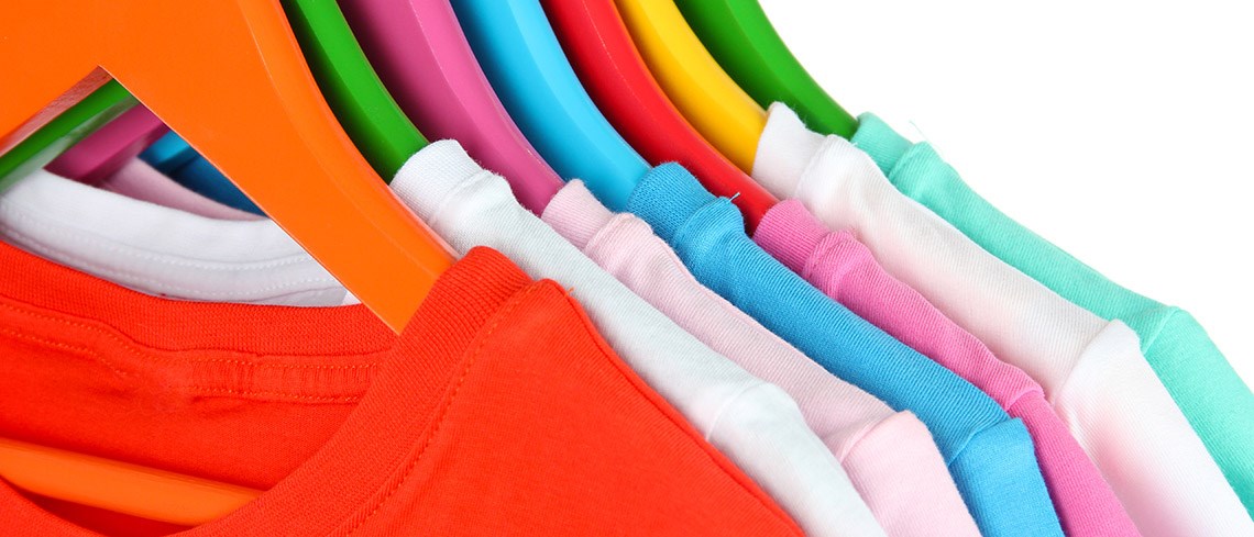 Colorful t-shirts hanging on hangers