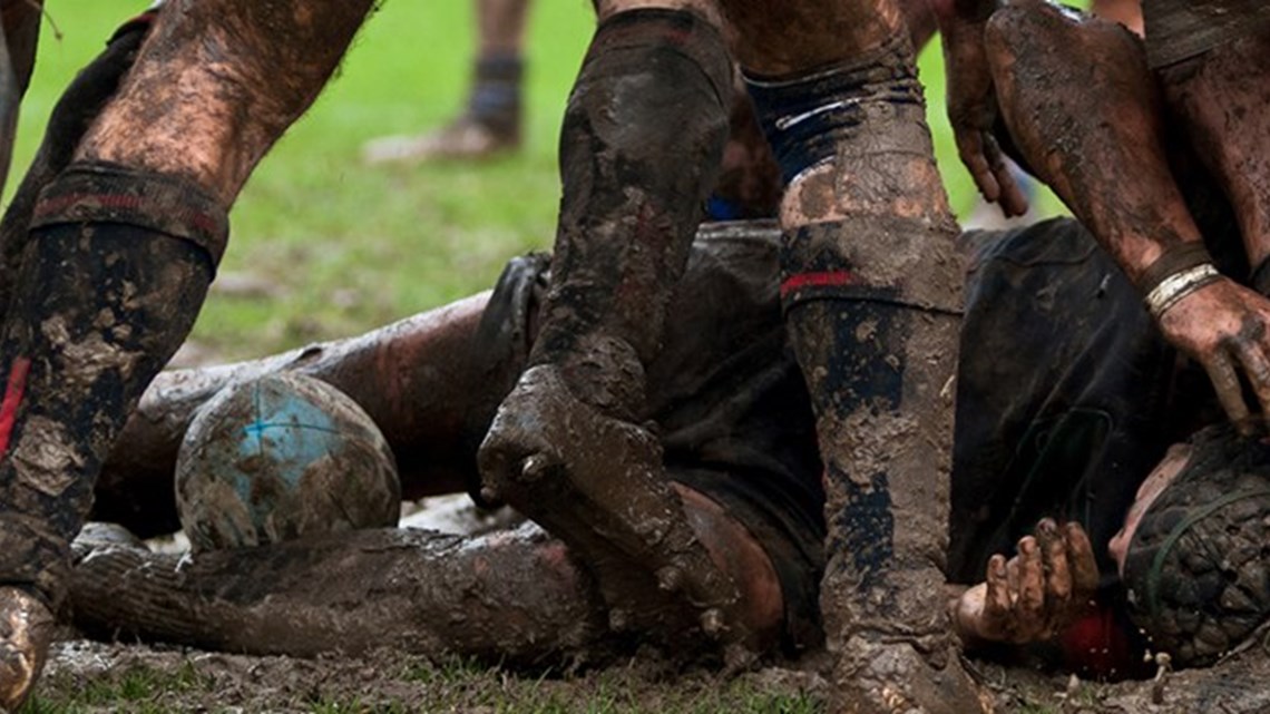 rugby players playing rugby in muddy playing field