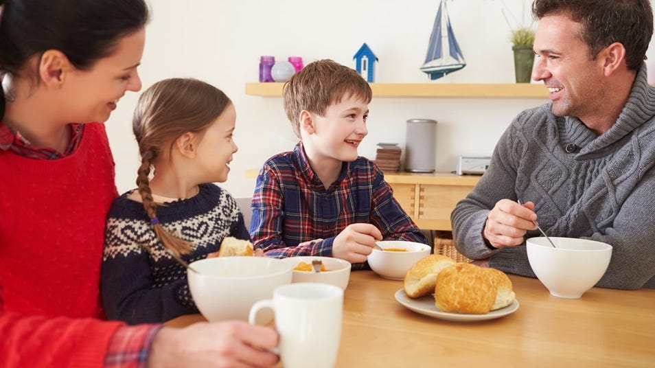a man, woman, and children eating together in a house