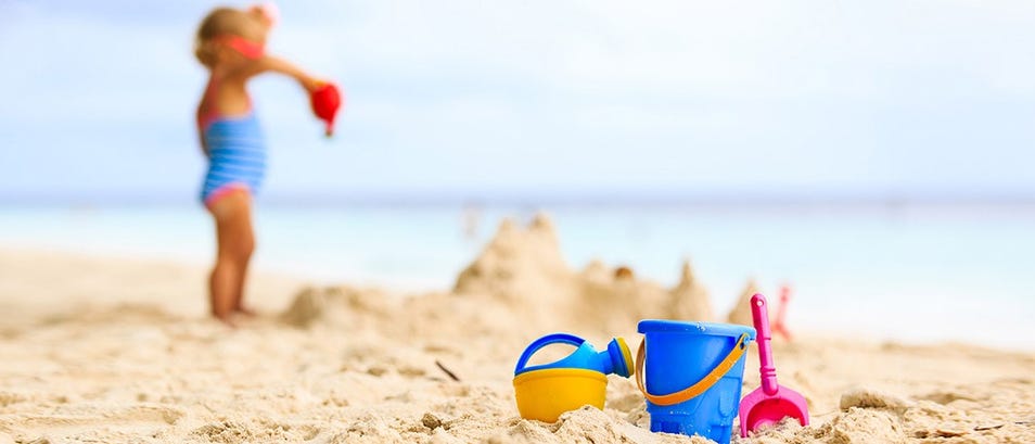 ألعاب الشاطئ على الرمال على الشاطئ مع وجود طفل في الخلفية