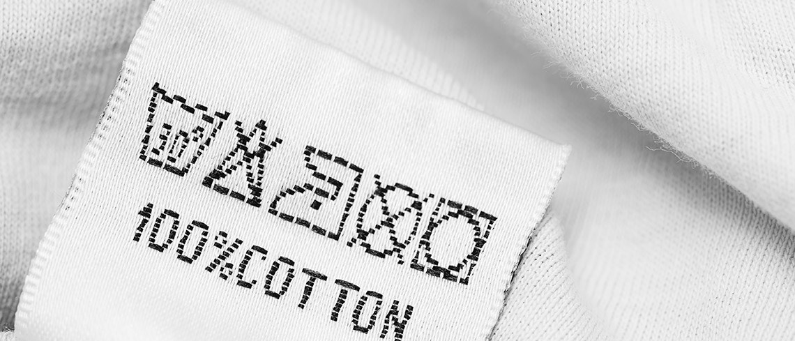 A close-up of a clothing label that says 100% COTTON