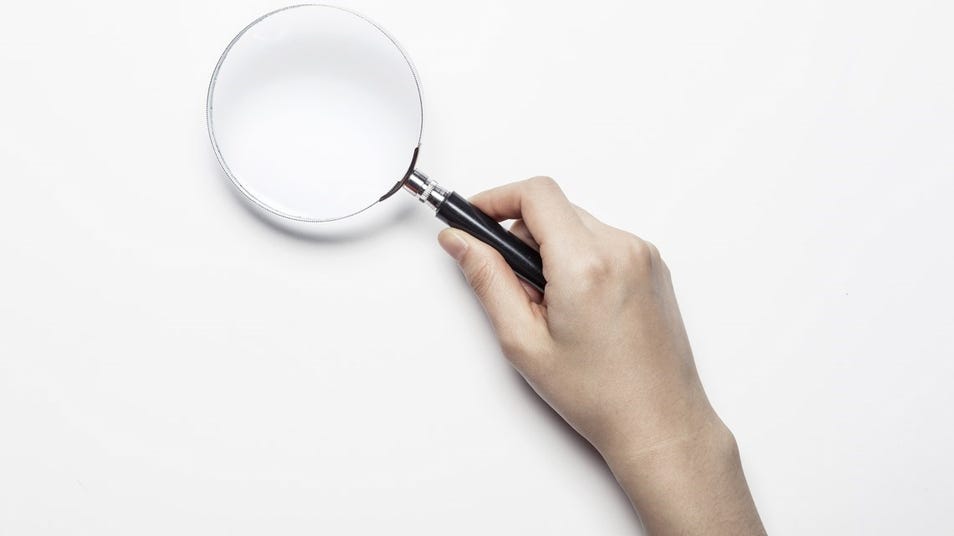 Hand holding a magnifying glass