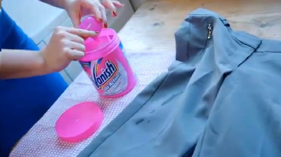 A woman applying Vanish stain remover to a grey shirt