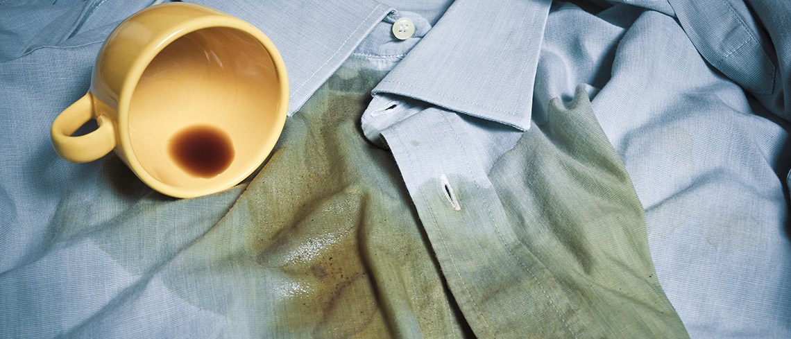 A yellow cup with coffee spilled on a blue shirt