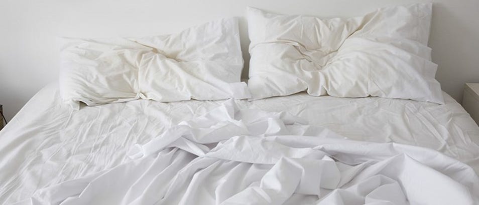 Unmade bed with crumpled sheets and pillows