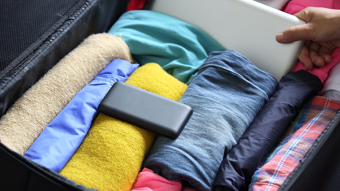 suitcase open with folded clothes and a power bank inside