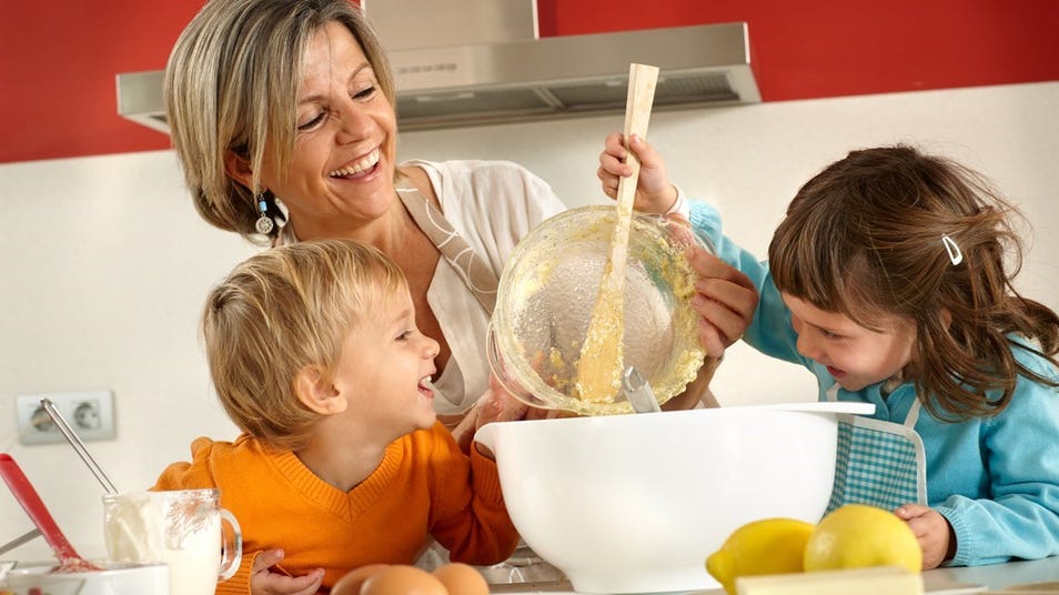 a woman and children having fun in the kitchen while making something