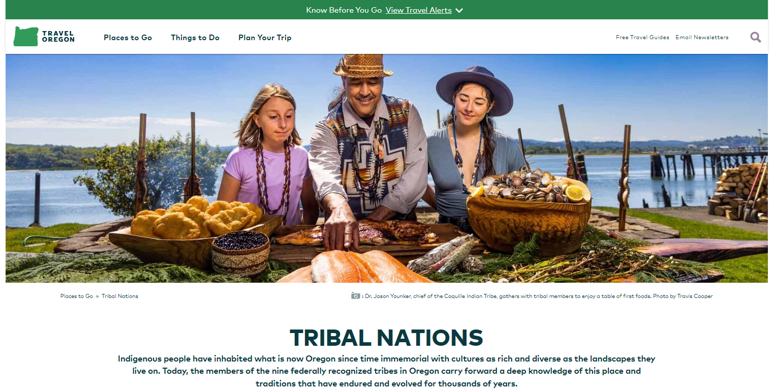 The Tribal Nations section under Places to Go on the Travel Oregon website depicts a Native American man demonstrating food preparation to a white woman and a white girl.