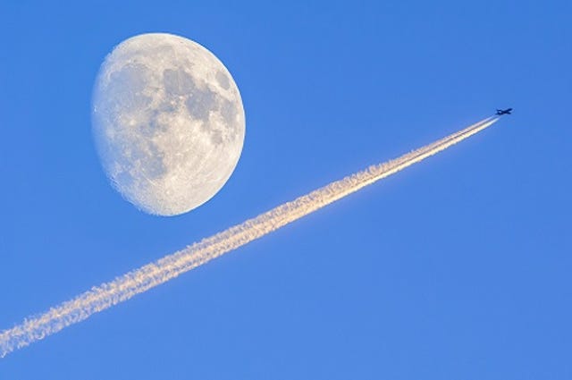 jet flying high with moon in background