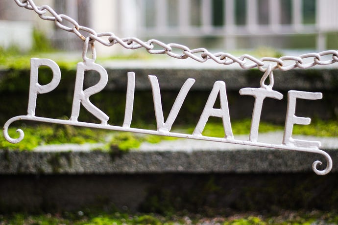 A white, metal "private" sign attached to a chain.