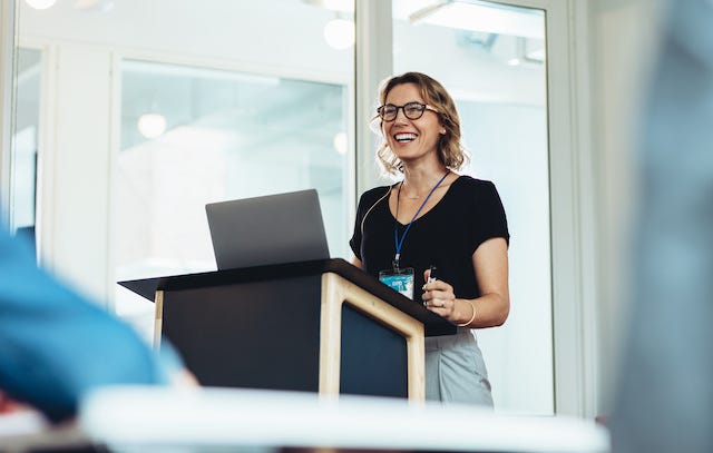 Woman in a black blouse gives a speech at a lectern