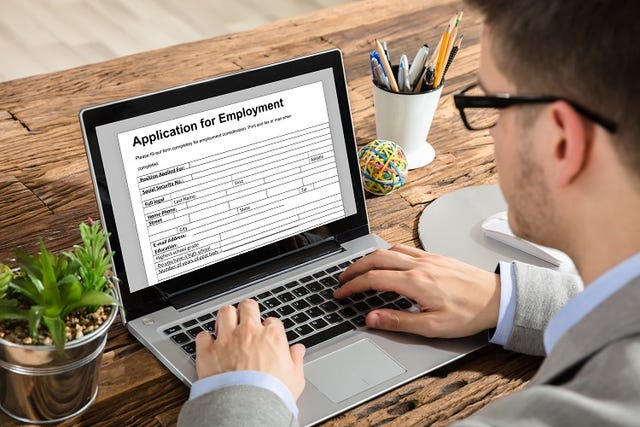 a job candidate filling out an employment application on the laptop.