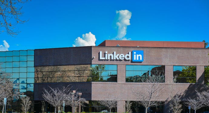 LinkedIn signage on a brick office building with a blue sky and puffy clouds overhead