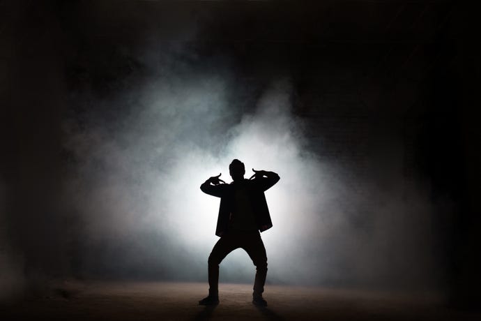 Silhouette of a b-boy striking a pose amid stage smoke