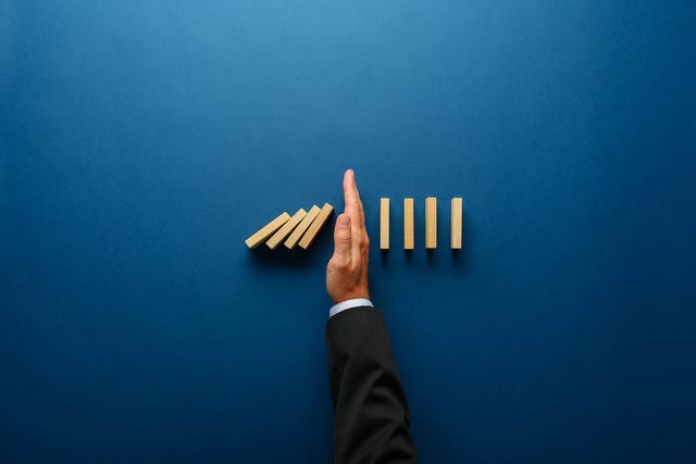 A man places his hand amid a row of dominoes or wood