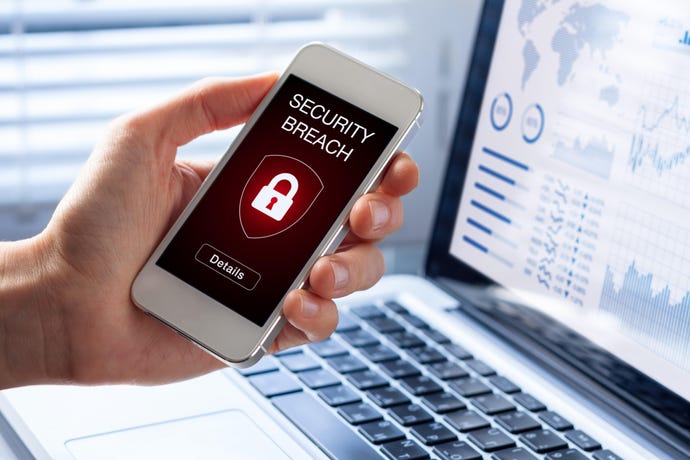 Hand holding a mobile phone near a laptop with the words "Security Breach" and a lock image on the device screen