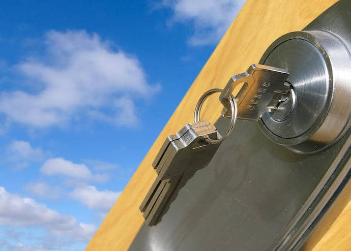 key in a door lock against a background of blue sky and clouds