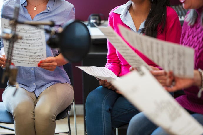 a group of people sitting and holding music sheets.