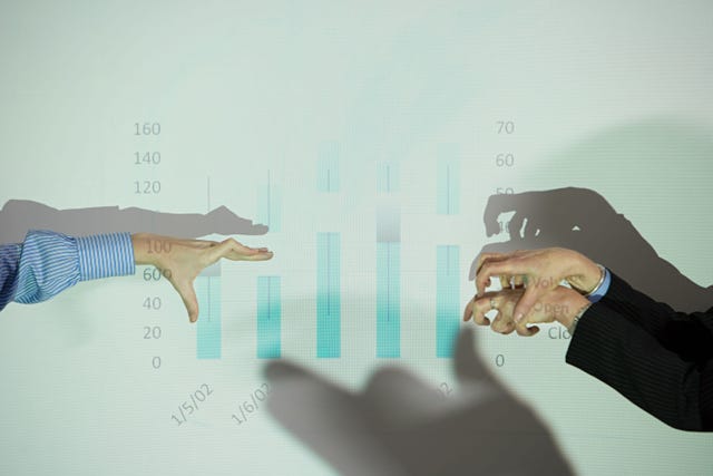 Image shows two hands playing shadow puppets in front of a data chart