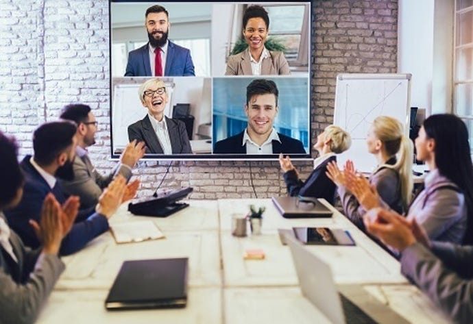 workers in a conference room with remote workers on a large screen having a conversation