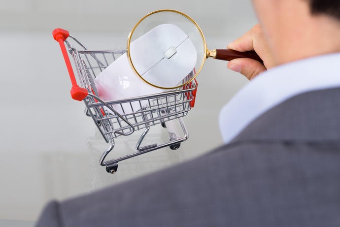 Photo illustration of a businessman inspecting a computer mouse in a miniature shopping cart through a magnifying glass