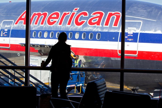 Passenger in airport terminal with American Airlines airplane outside window