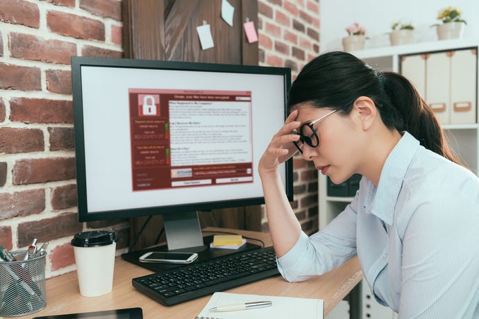 woman sitting in front of computer that is infected with ransomware