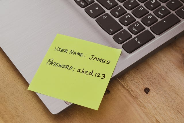 A person's username and a weak choice of password handwritten in sticky note on laptop. Concept of resetting password.