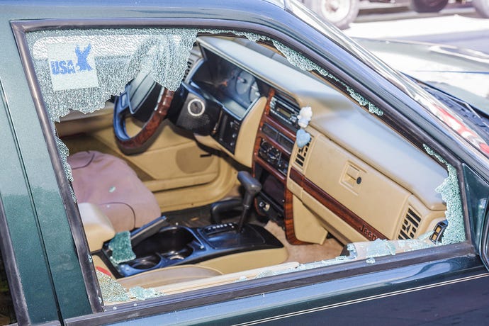 Photo of the aftermath of a car burglary, with the passenger side window smashed and safety glass pieces everywhere