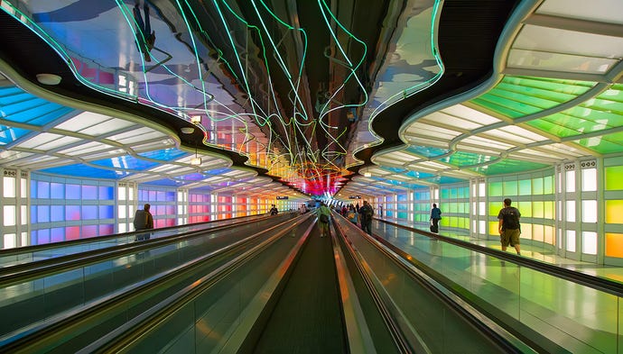 Underground passage connecting terminals of the Chicago O'Hare airport; rows of people movers and tons of abstract neon lights
