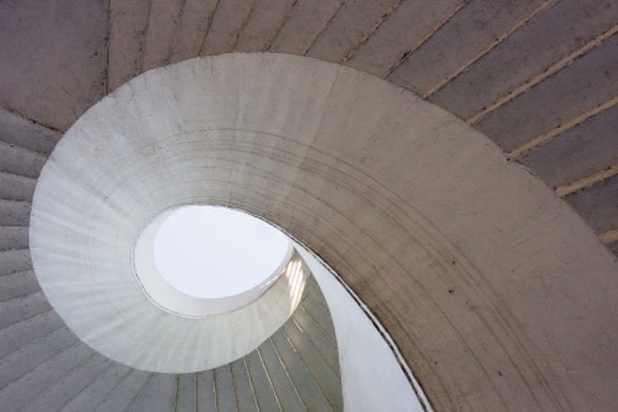 A photo looking up through a brutalist concrete spiral staircase