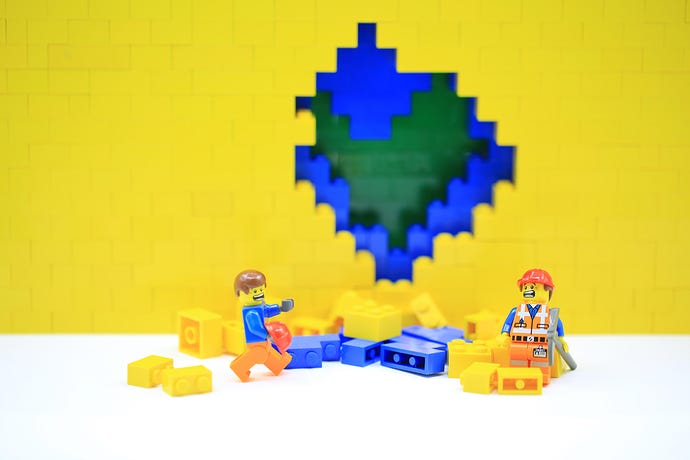 Photo of a scene of a construction worker repairing a wall while random guy walks through, all built of Lego bricks