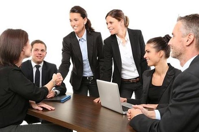 Group of people in suits around a table for what looks like a job interview.