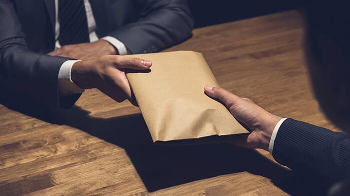 Businessman giving money in the envelope to a partner in the dark.